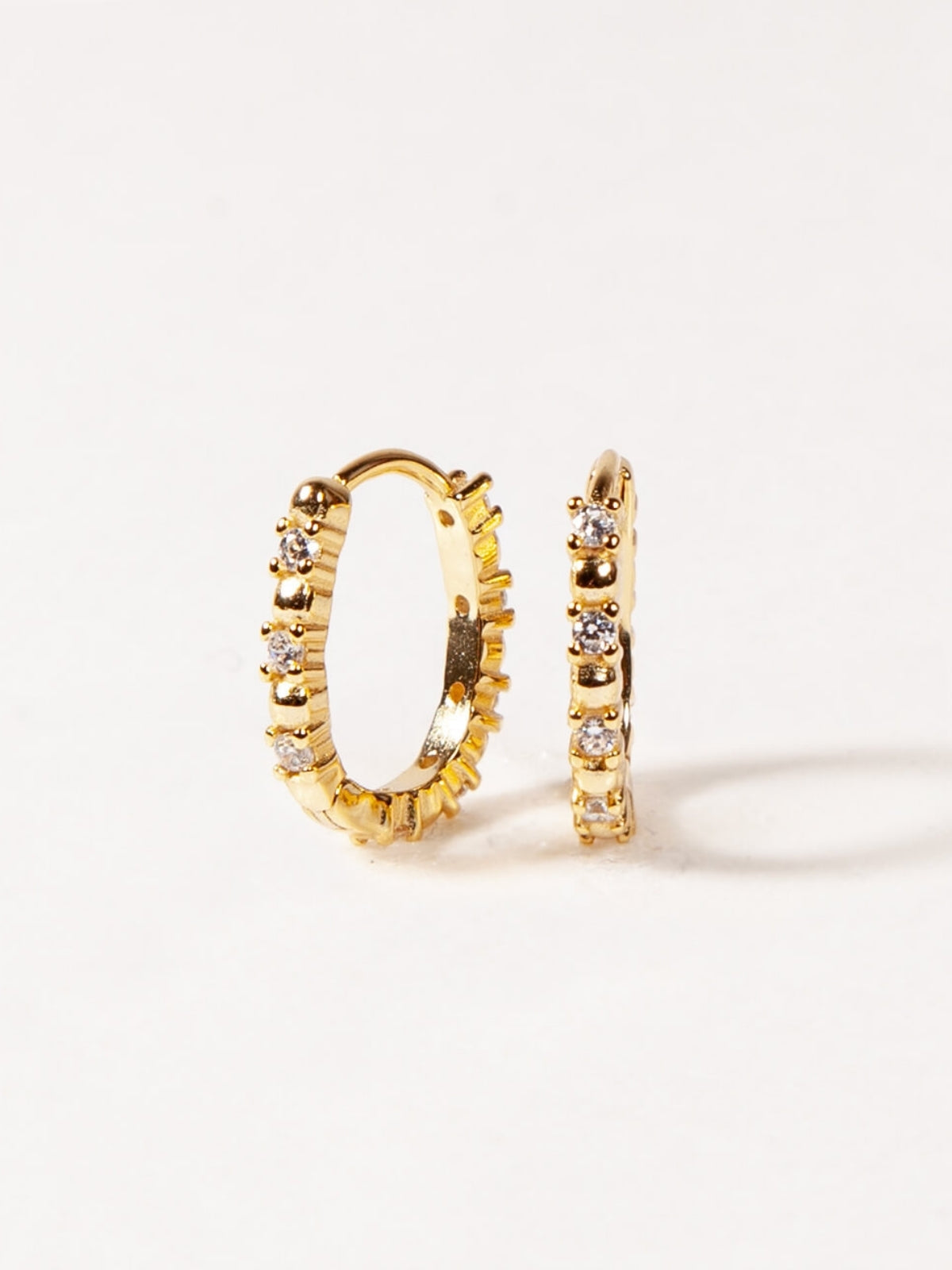 Gold hoop earrings with embedded stones on a white background