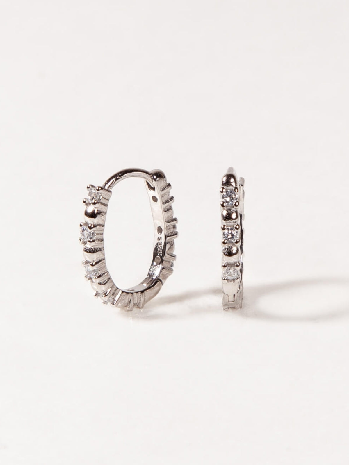 Pair of silver hoop earrings with diamond accents on a white background