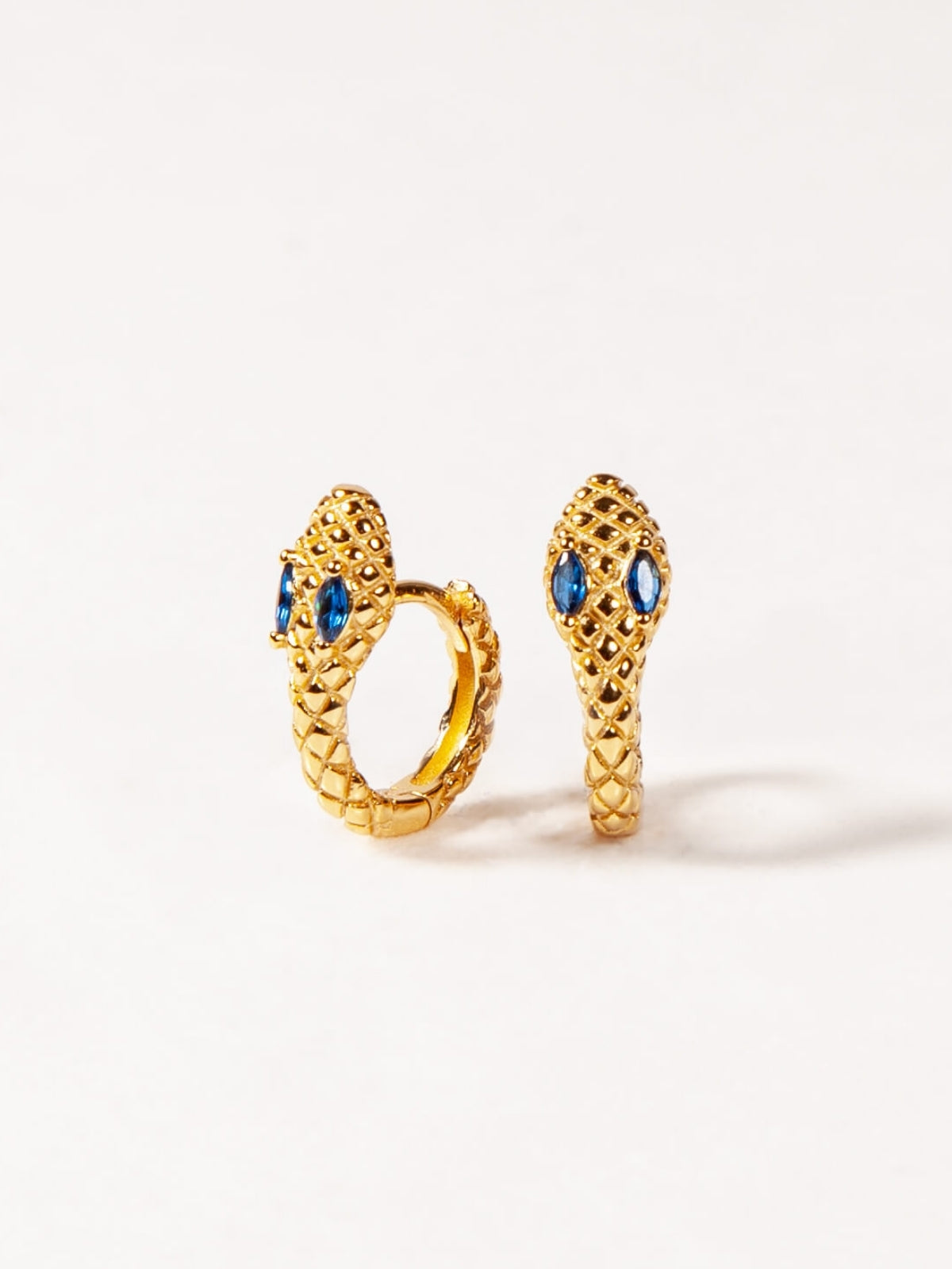 Pair of gold earrings with blue gemstones on a white background