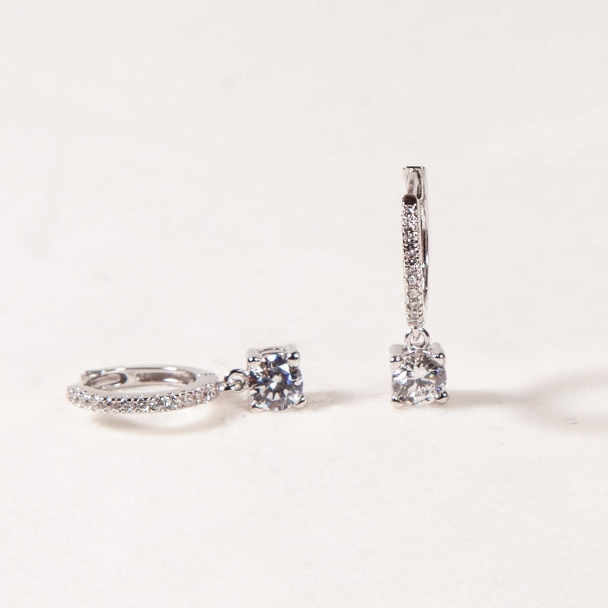 Diamond ring and earrings on a light gray background