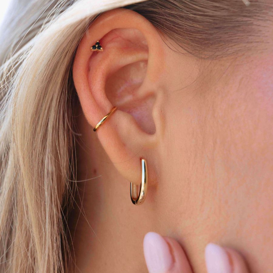 Close-up of an ear wearing gold hoop earrings