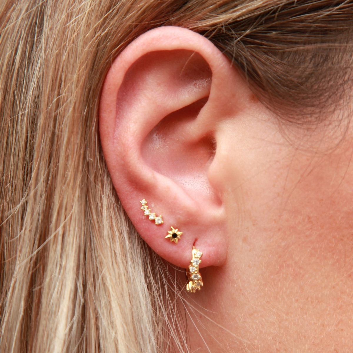 Close-up of an ear with gold earrings and hair.