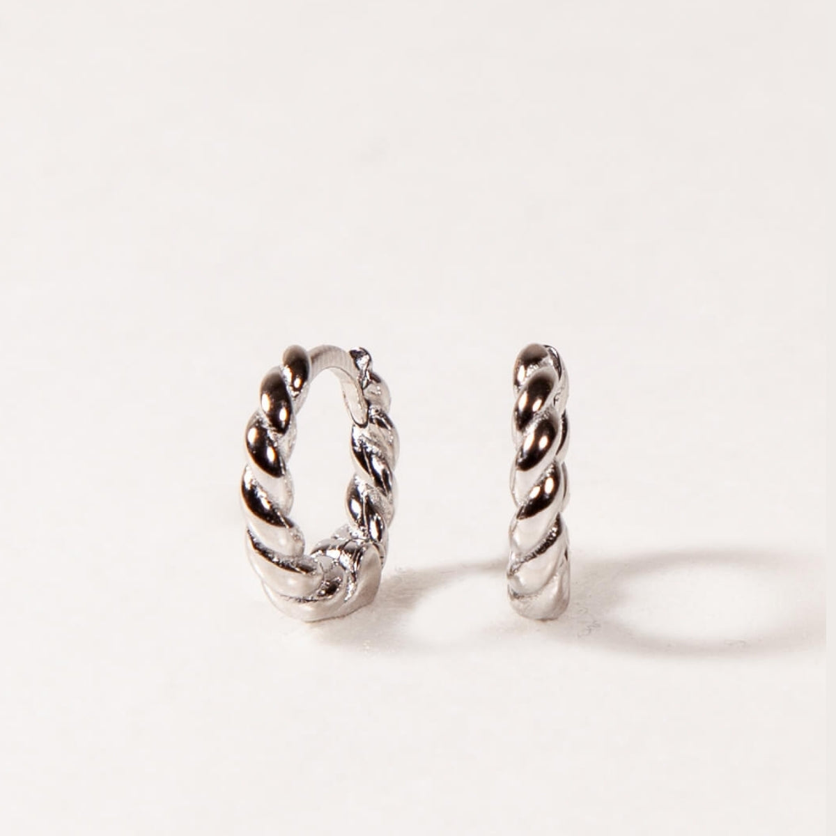 Pair of silver twisted hoop earrings on a white background