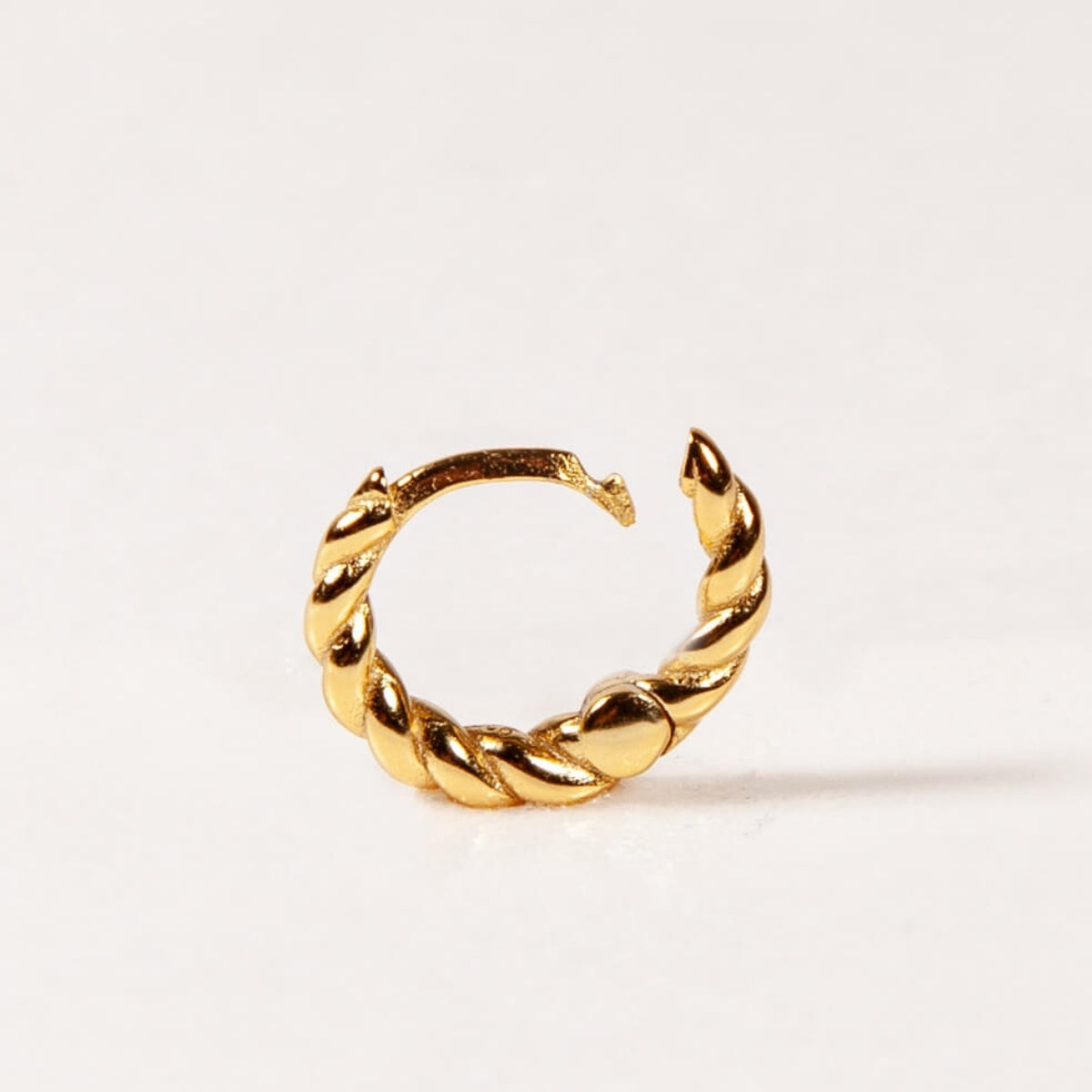 Gold twisted hoop earring on a white background