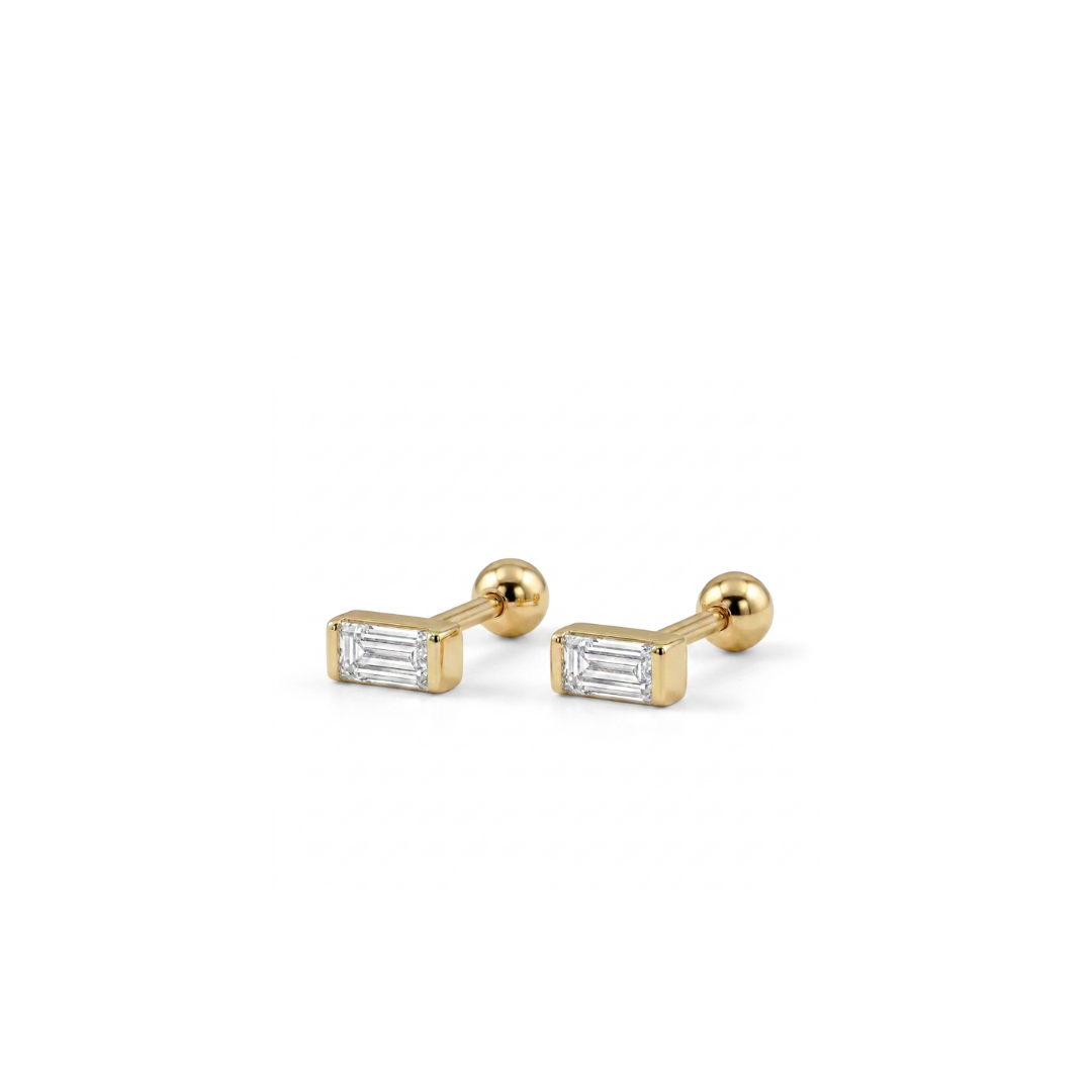 A pair of gold cufflinks with rectangular baguette-cut clear gemstones, shown on a clean white background.