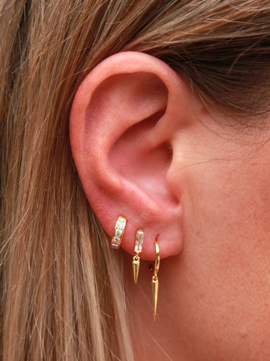 Close-up of an ear wearing gold hoop earrings with a blurred background