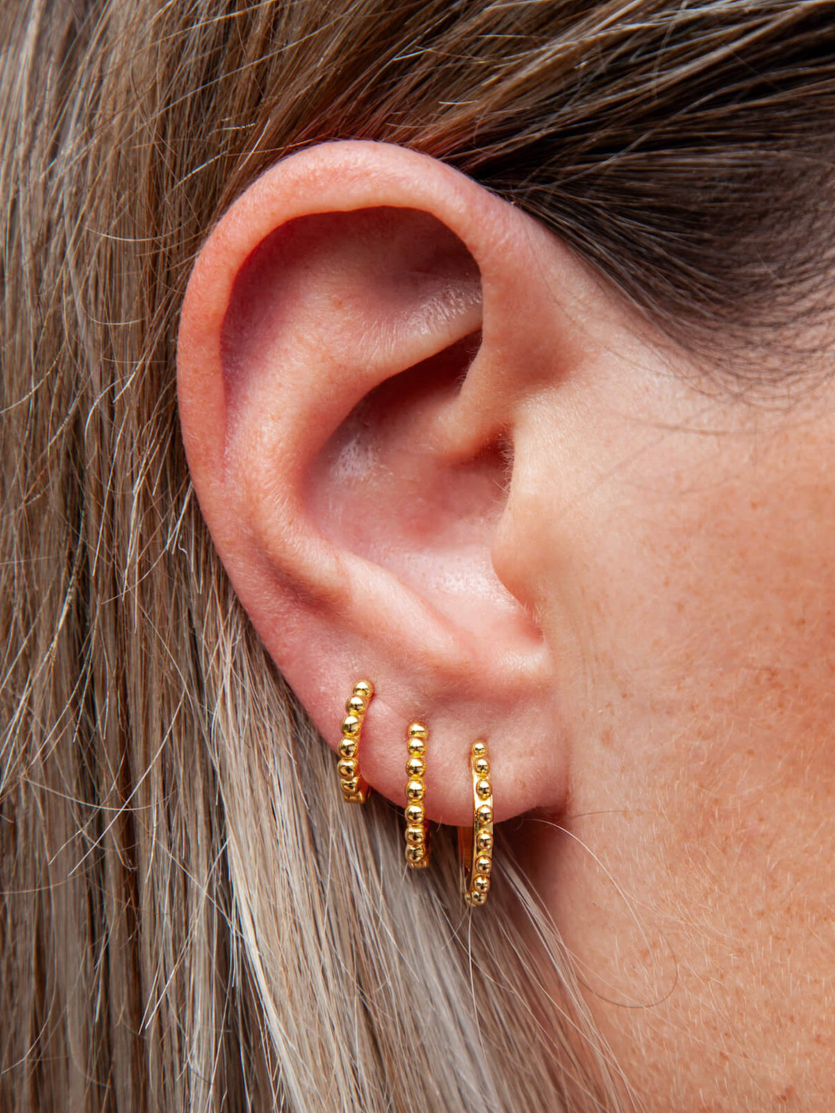 a woman's ear with hoops earrings with bead details