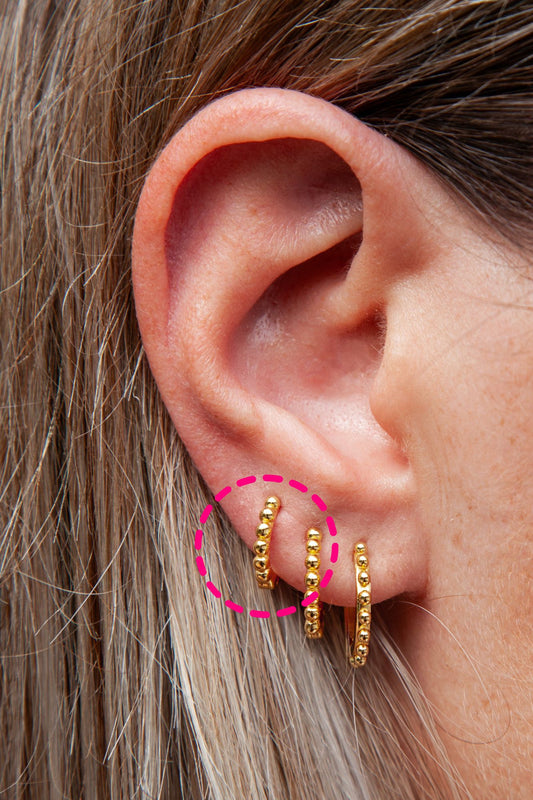 a woman's ear with hoops earrings with bead details