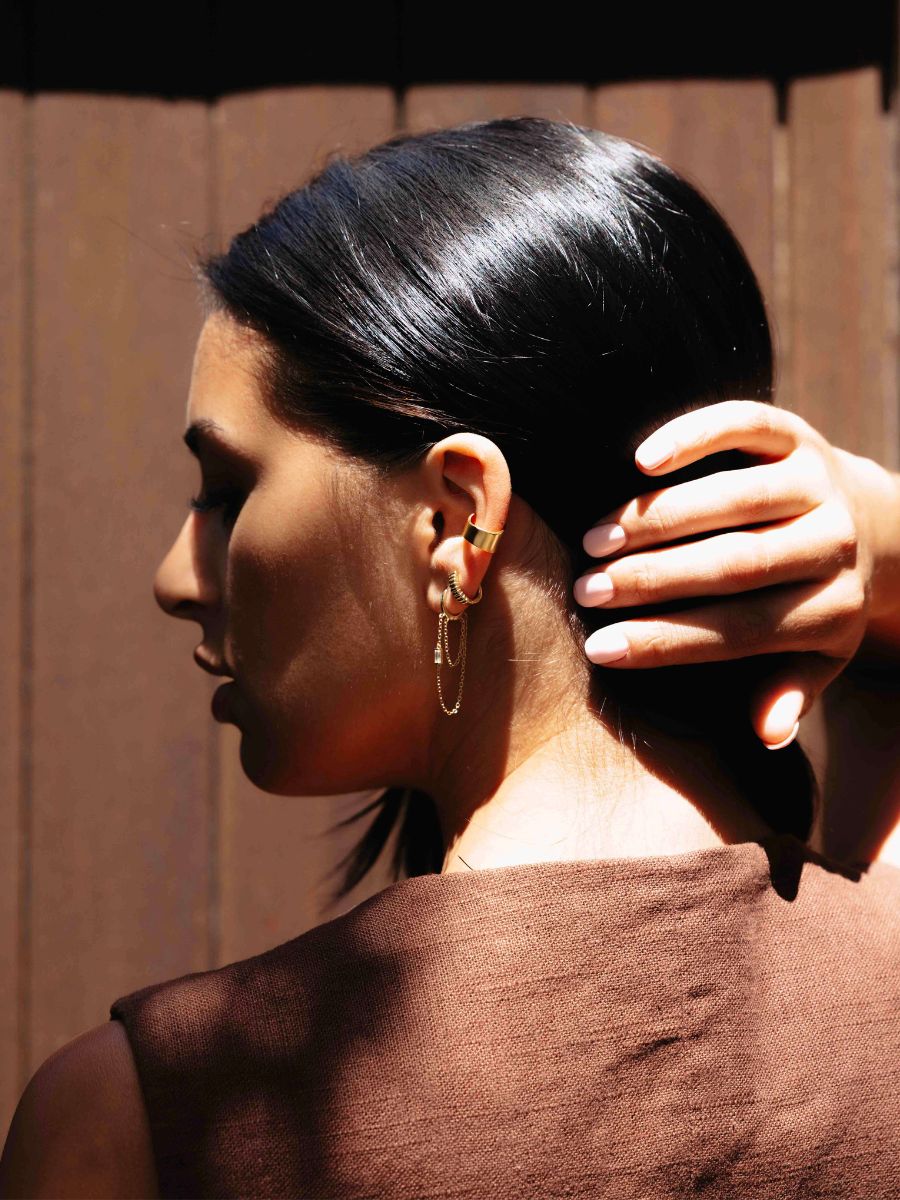A woman wearing chain huggies with linen brown top