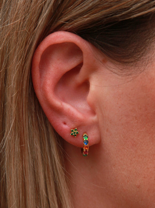 Close-up of an ear wearing colorful hoop earrings with a blurred background