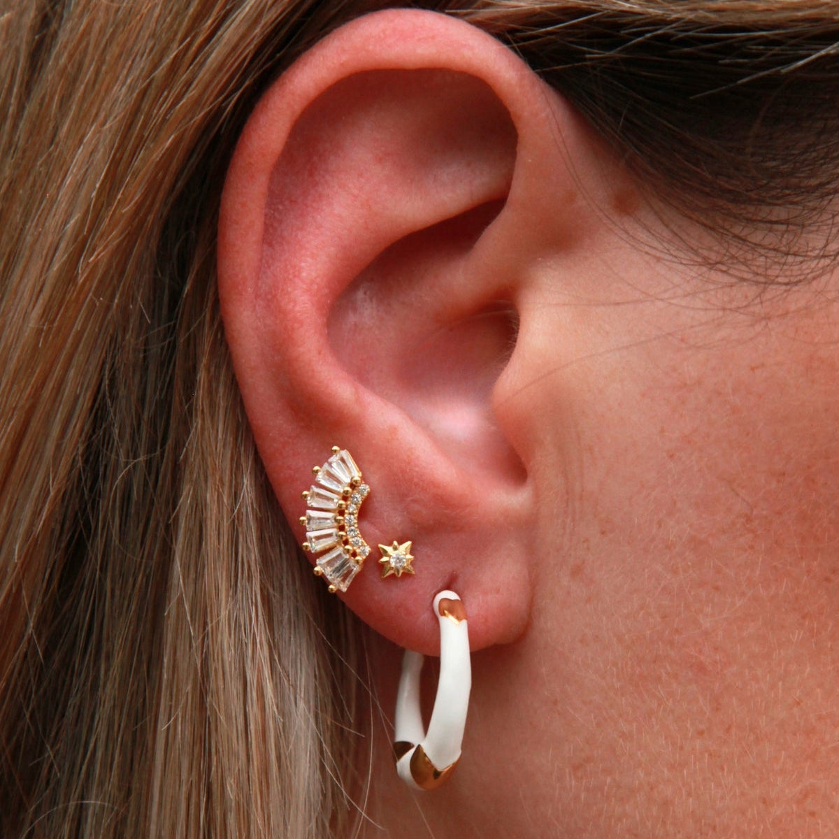 Close-up of an ear with gold and white earrings
