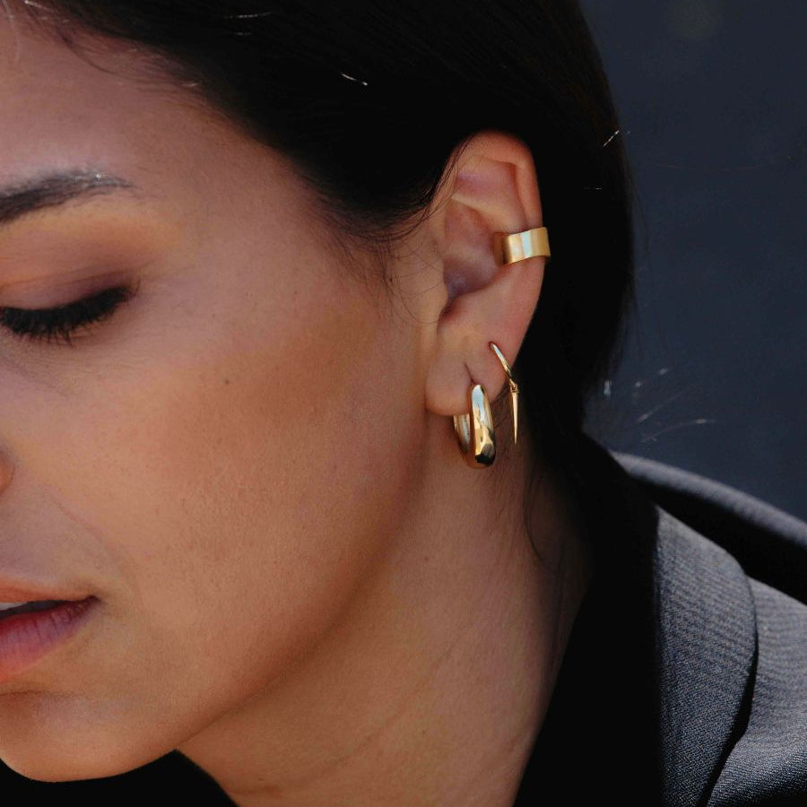 A woman wearing gold Wide Reversible Ear Cuff