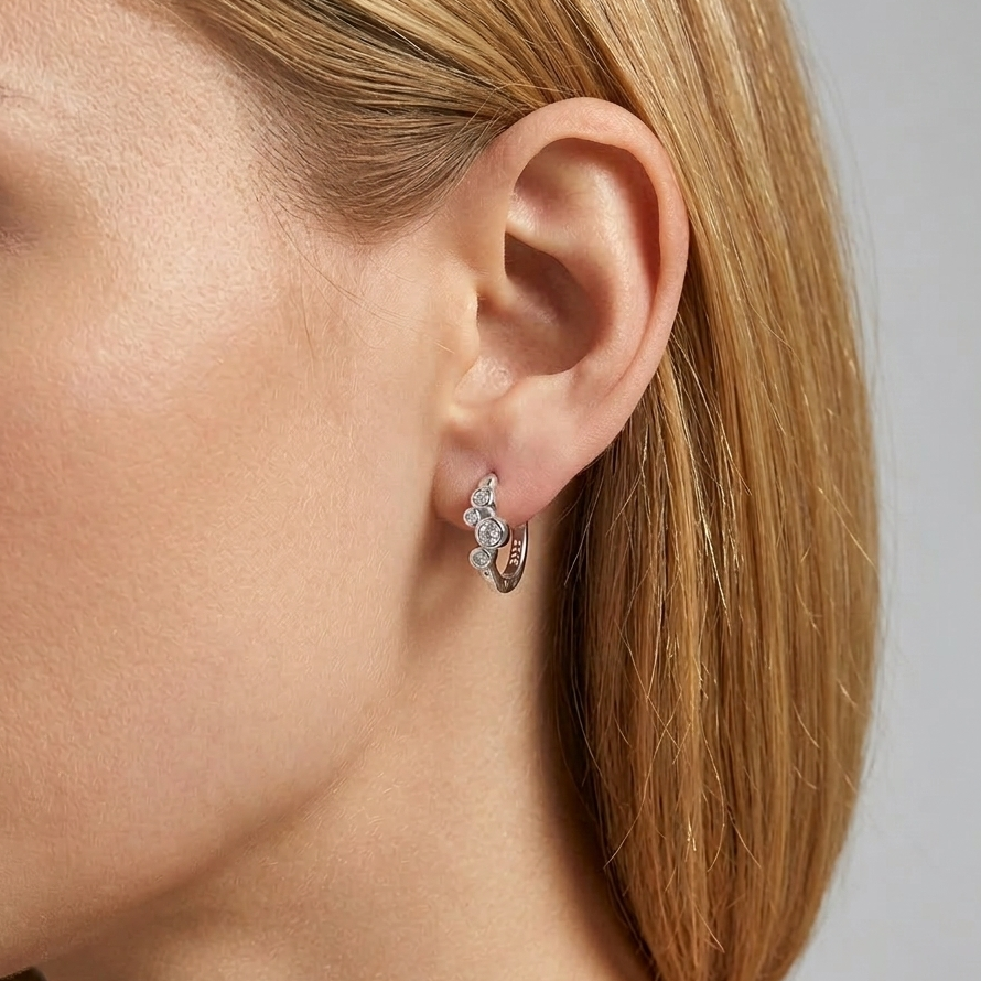 Close-up of a person wearing a bubble cz hoop earring on a neutral background
