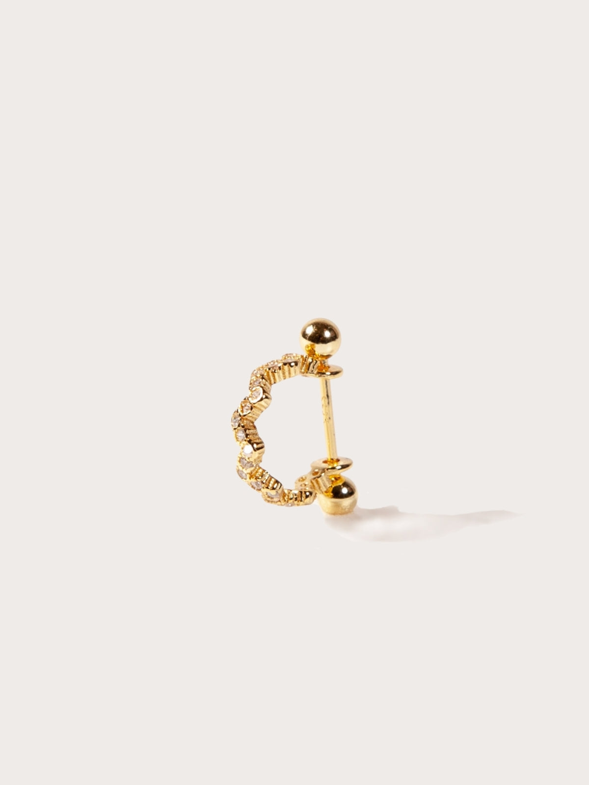 Gold earring for helix on a light beige background
