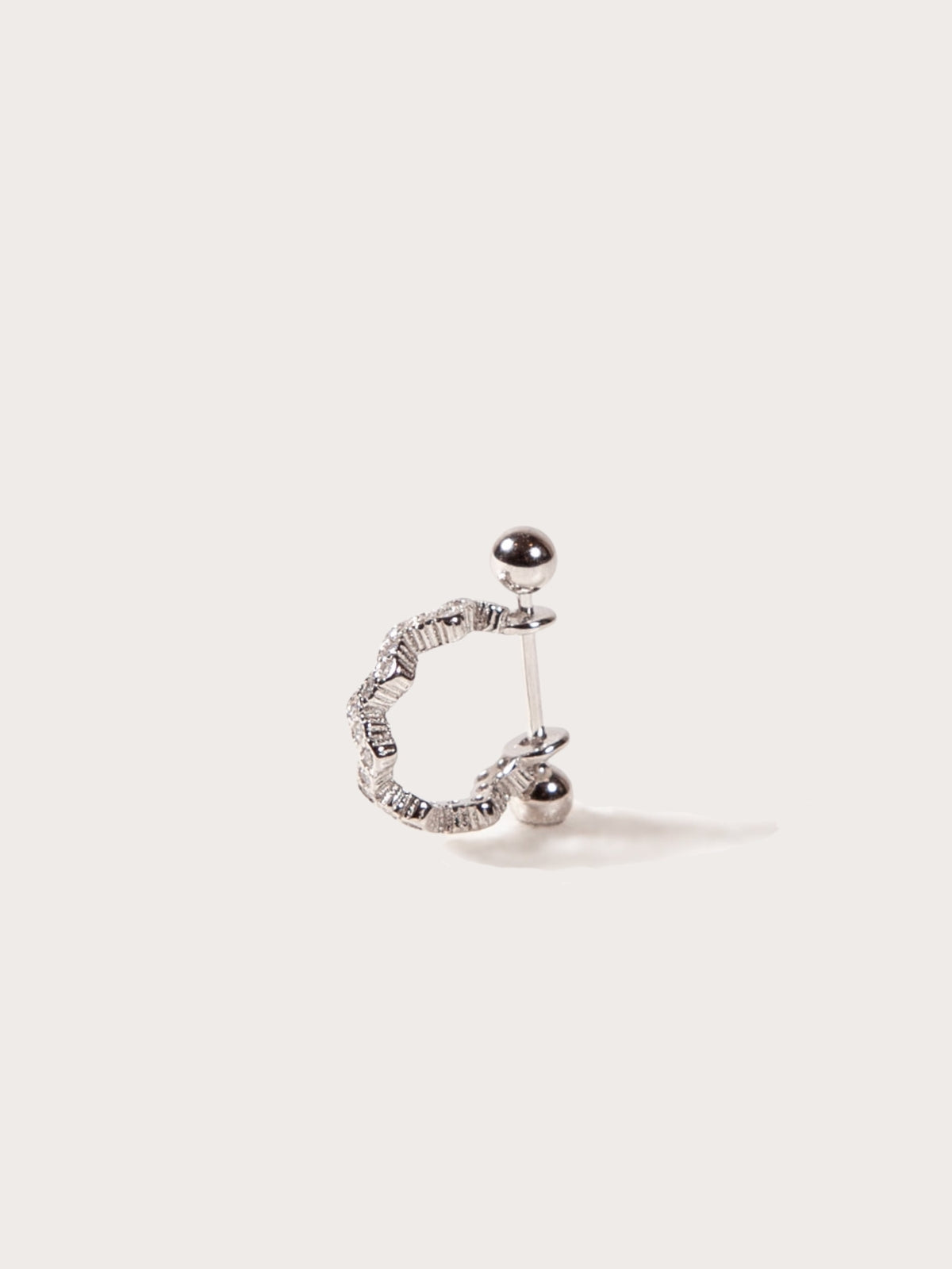 Silver earring for helix on a light beige background