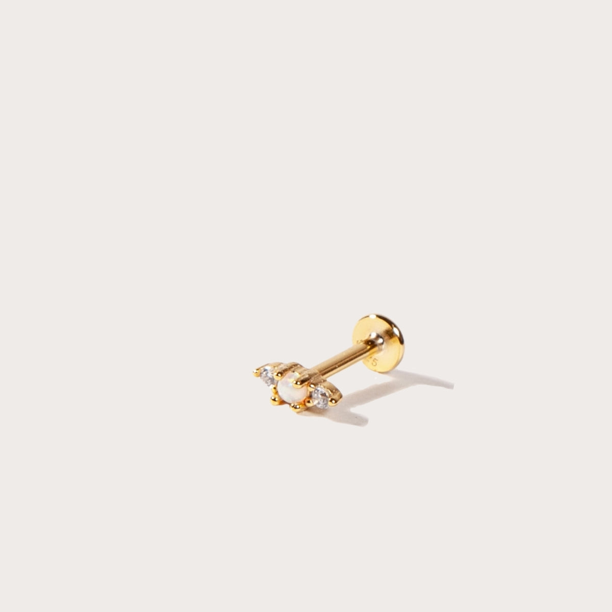 Gold flatback earring with a clear gemstone on a white background