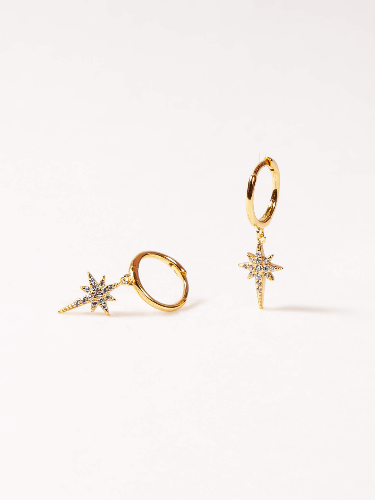 Gold star-shaped earrings and ring on a white background