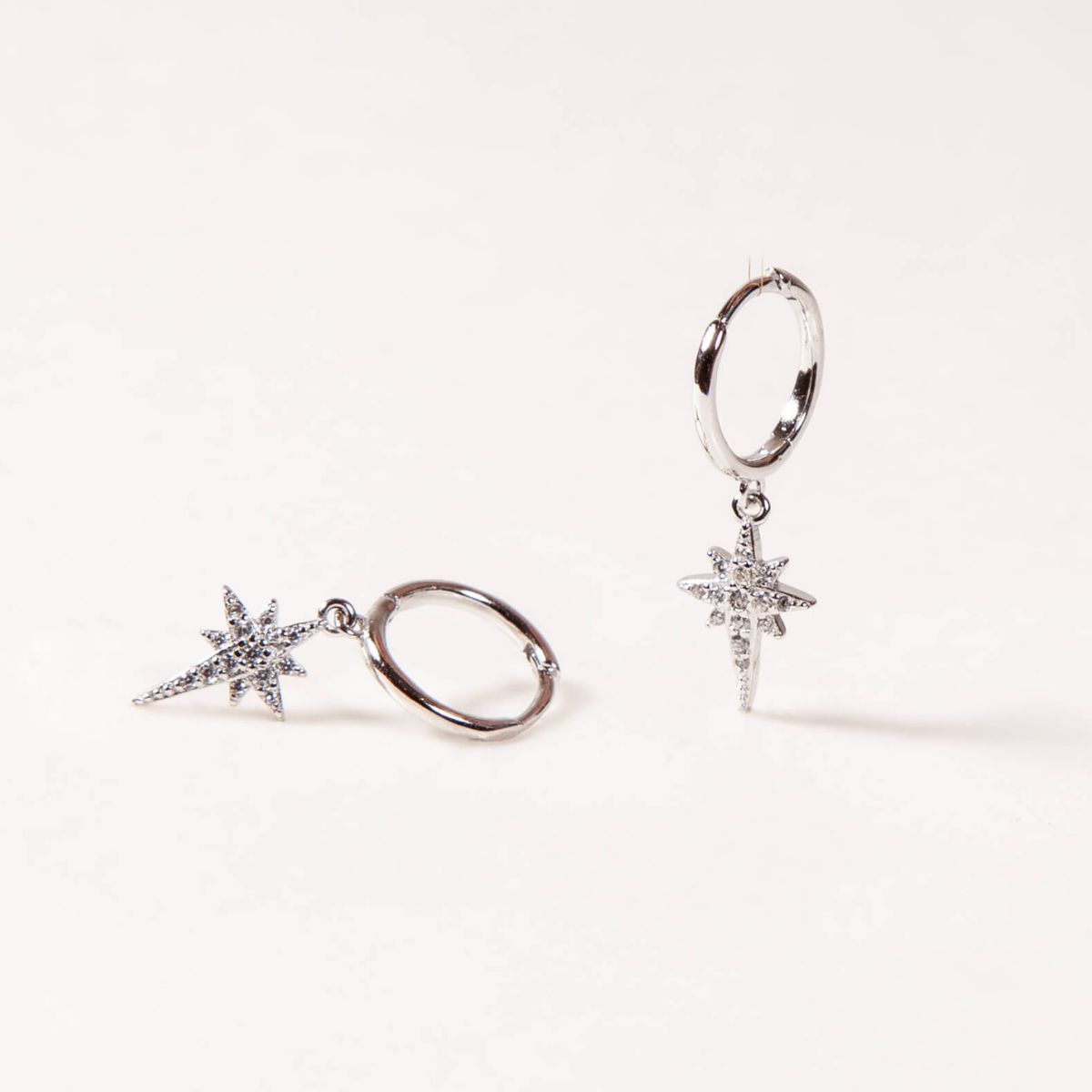 Pair of silver hoop earrings with star-shaped charms on a white background