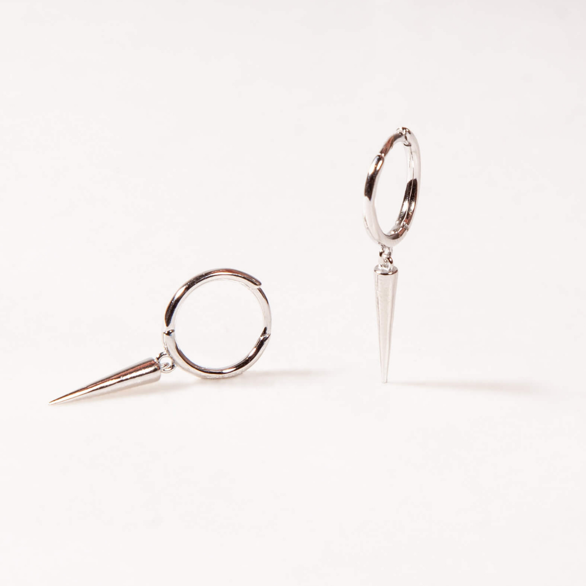 Pair of silver huggies with bar dangle earrings on a light gray background