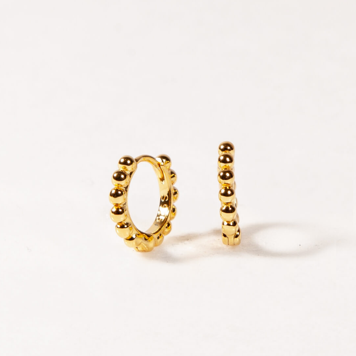 Gold hoop earrings with beads on a white background