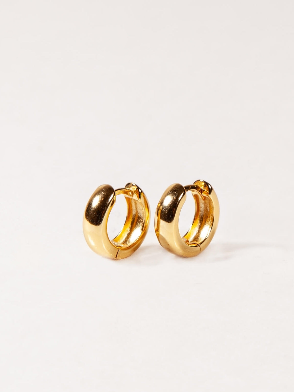 Pair of gold Chunky hoop earrings on a white background