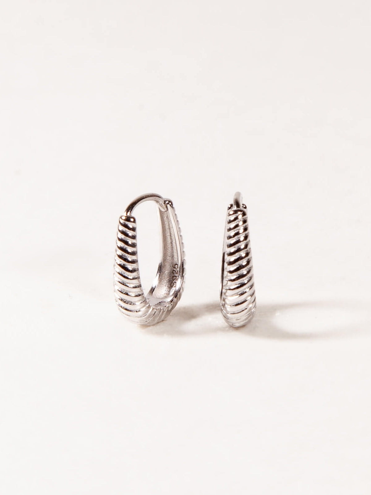 Pair of silver Oval hoop earrings on a white background
