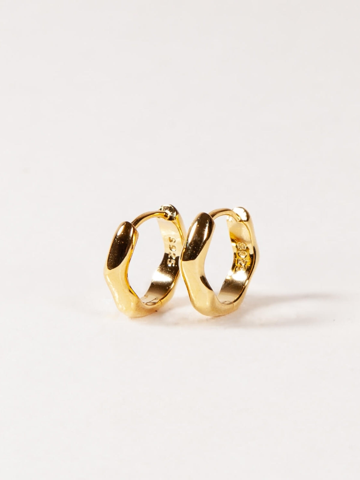 modern wave huggies earrings on a white background