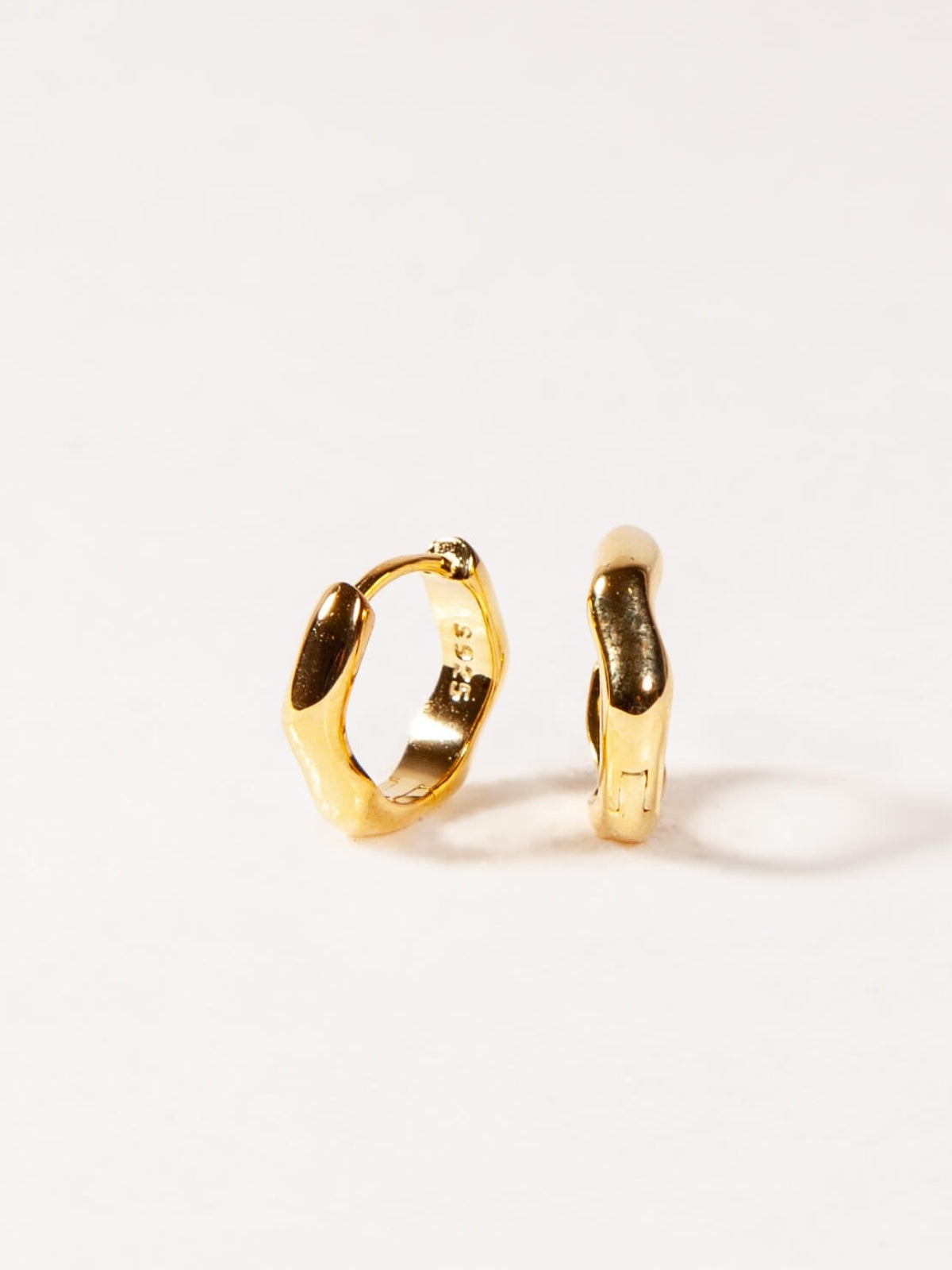 modern wave huggies earrings on a white background