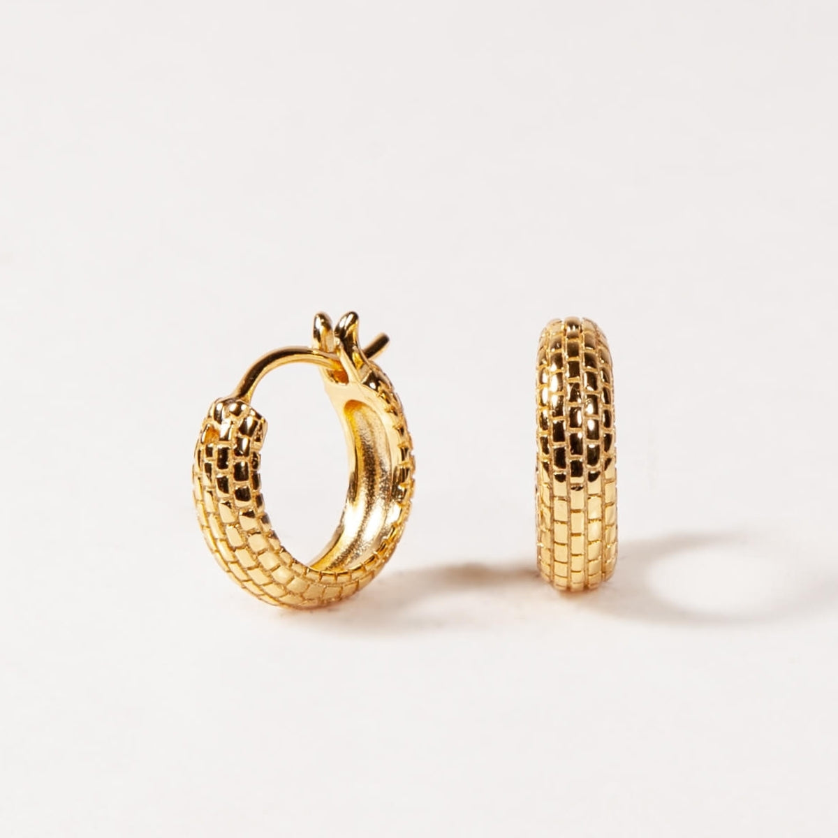 Gold hoop earrings with textured design on a white background