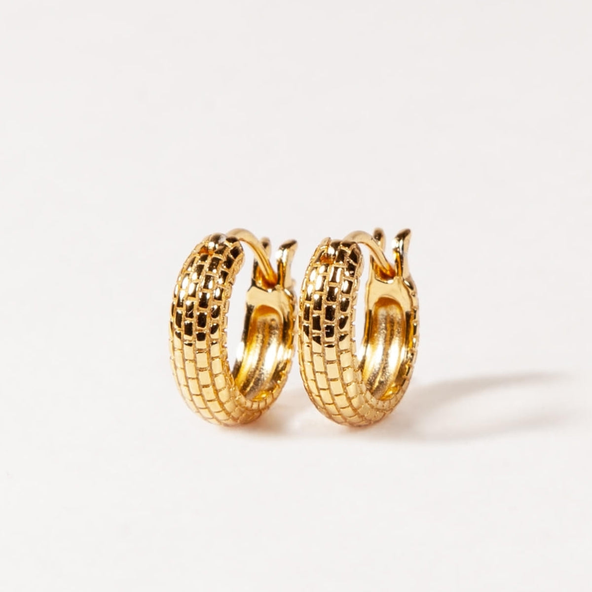 Pair of gold hoop earrings on a light gray background