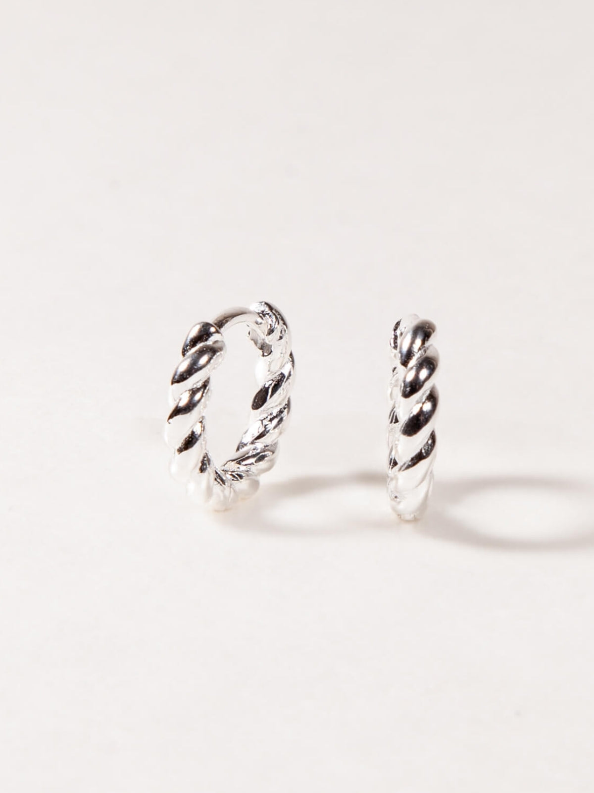Pair of silver twisted hoop earrings on a white background