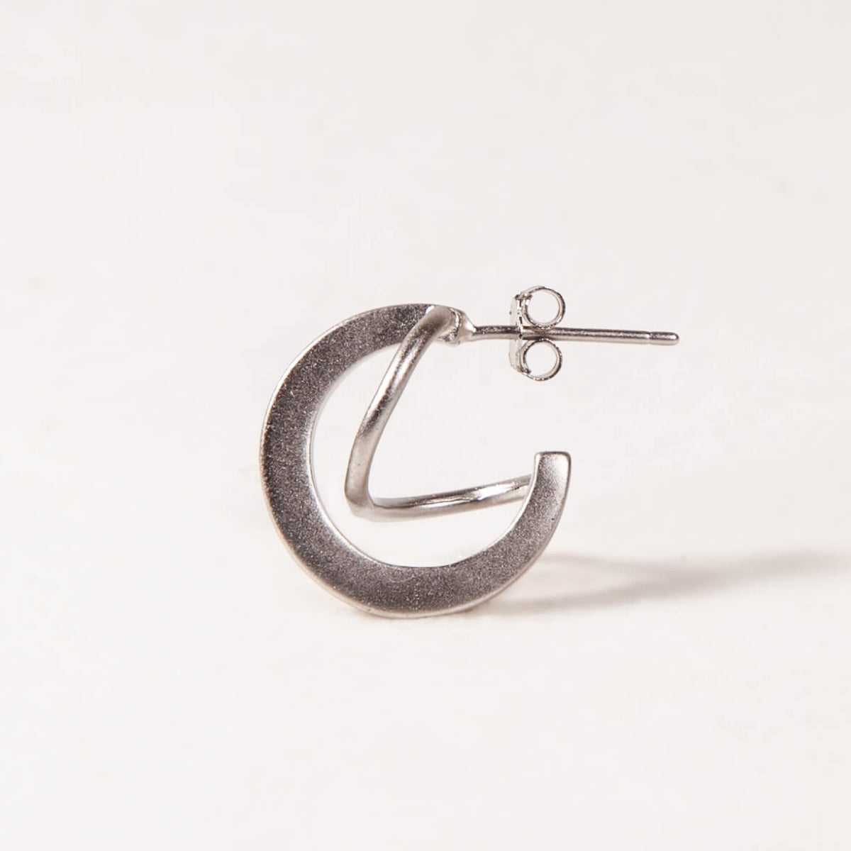 Silver crescent moon earring on a white background