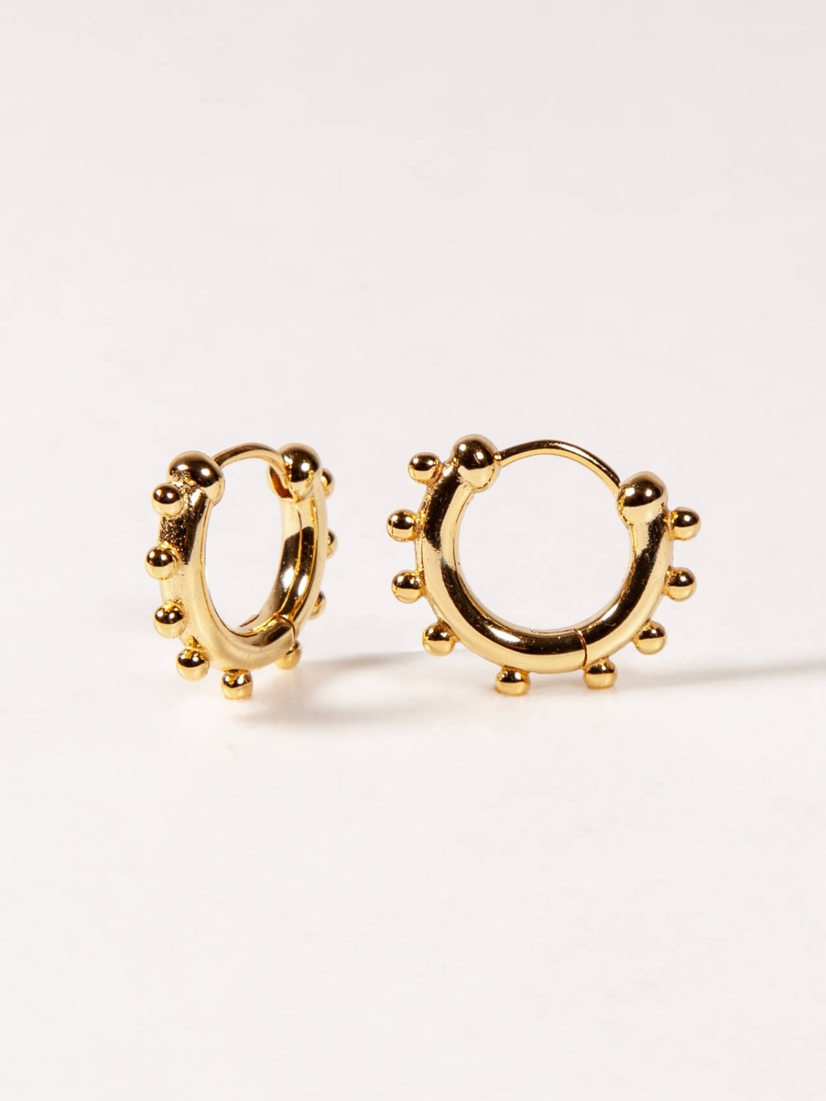 Gold hoop earrings on a light beige background