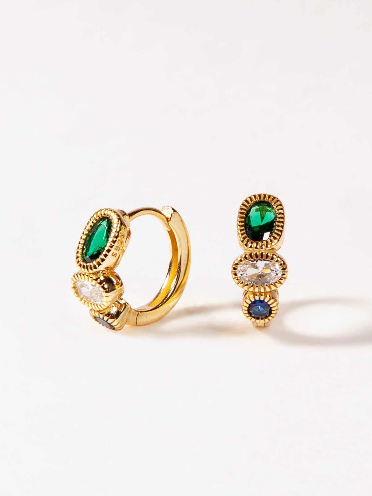 Gold hoop earrings with green and blue gemstones on a white background