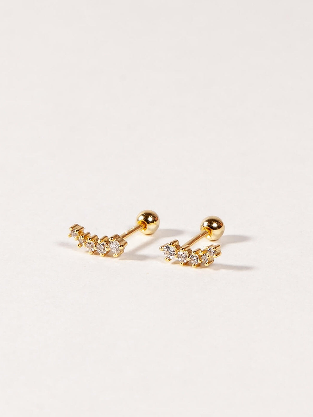 A pair of gold stud earrings with cubic zirconia stones, designed in a shooting star shape, displayed against a white background.