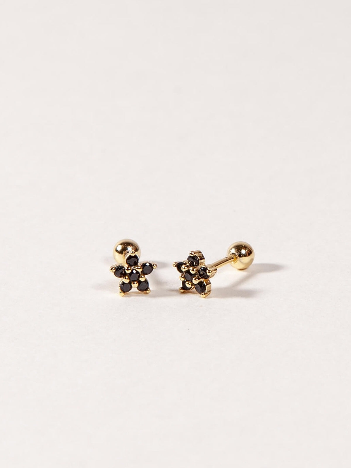 Pair of gold flower-shaped earrings with Black CZ stones on a white background