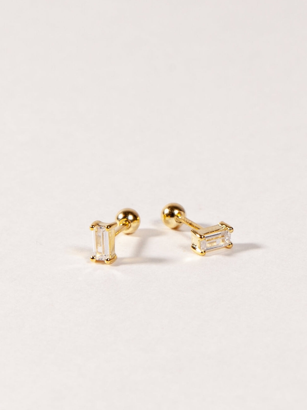 Gold baguette earrings on a light gray background