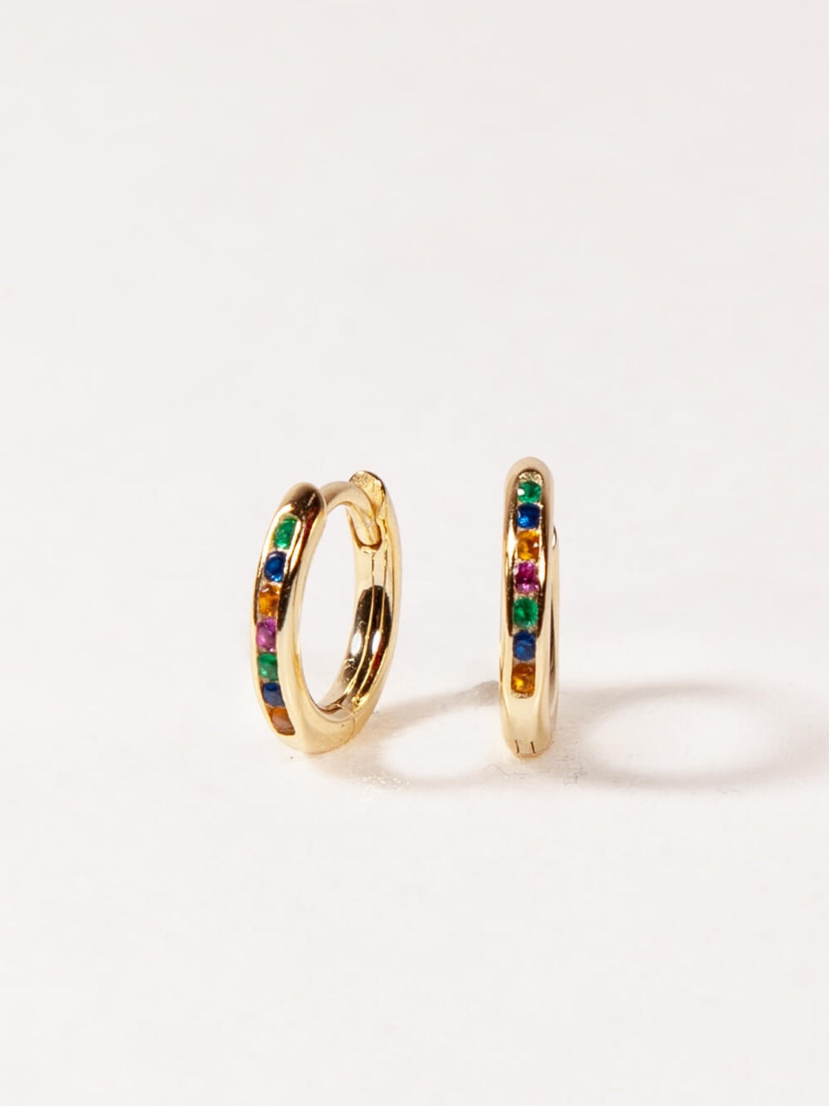 Gold hoop earrings with colorful gemstones on a white background