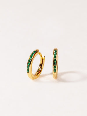 Gold hoop earrings with green gemstones on a white background
