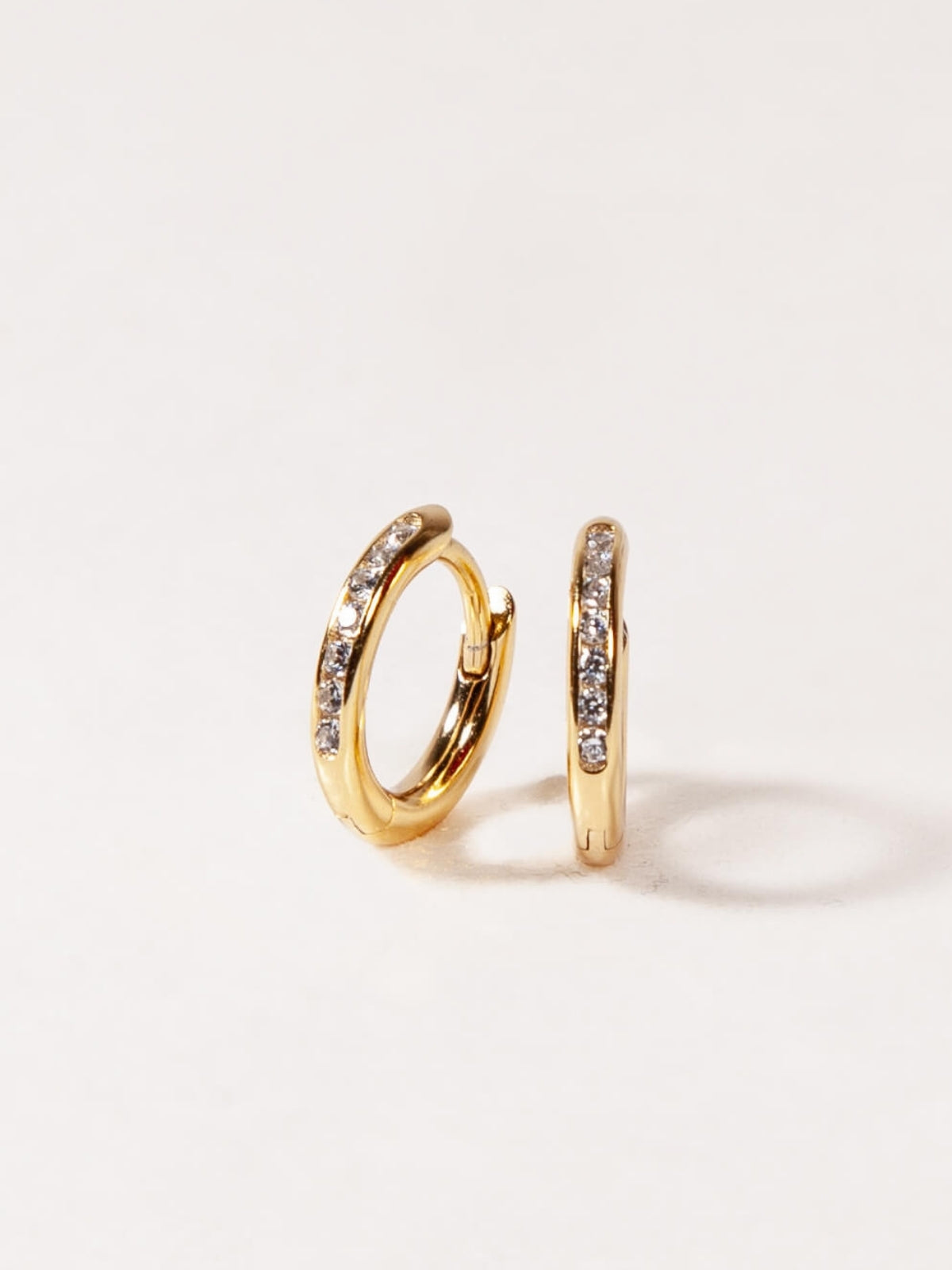 Gold hoop earrings with embedded stones on a light background