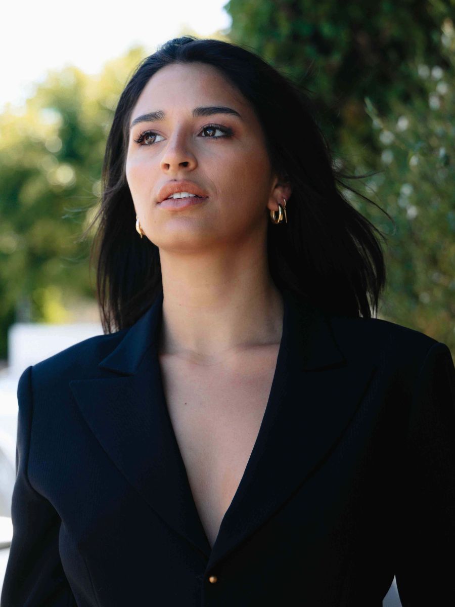 a woman wearing black suit with black hair wearing gold earrings