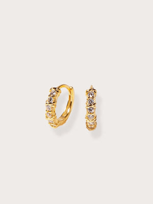 Gold hoop earrings with embedded stones on a light beige background