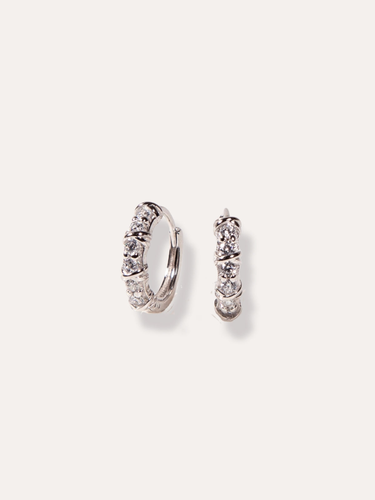 Pair of silver hoop earrings with clear gemstones on a light gray background