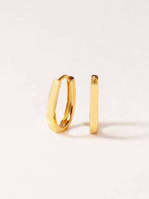 Two gold hoop earrings on a light beige background