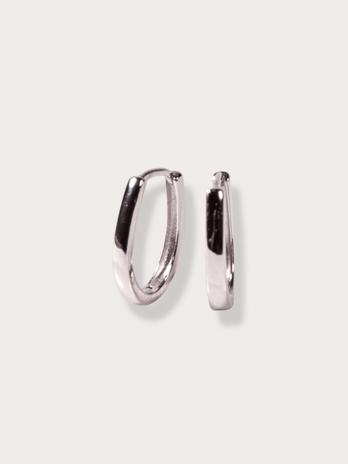 Pair of silver oval hoop earrings on a light gray background