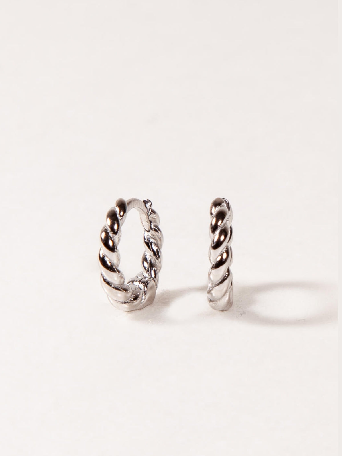 Pair of silver twisted hoop earrings on a white background