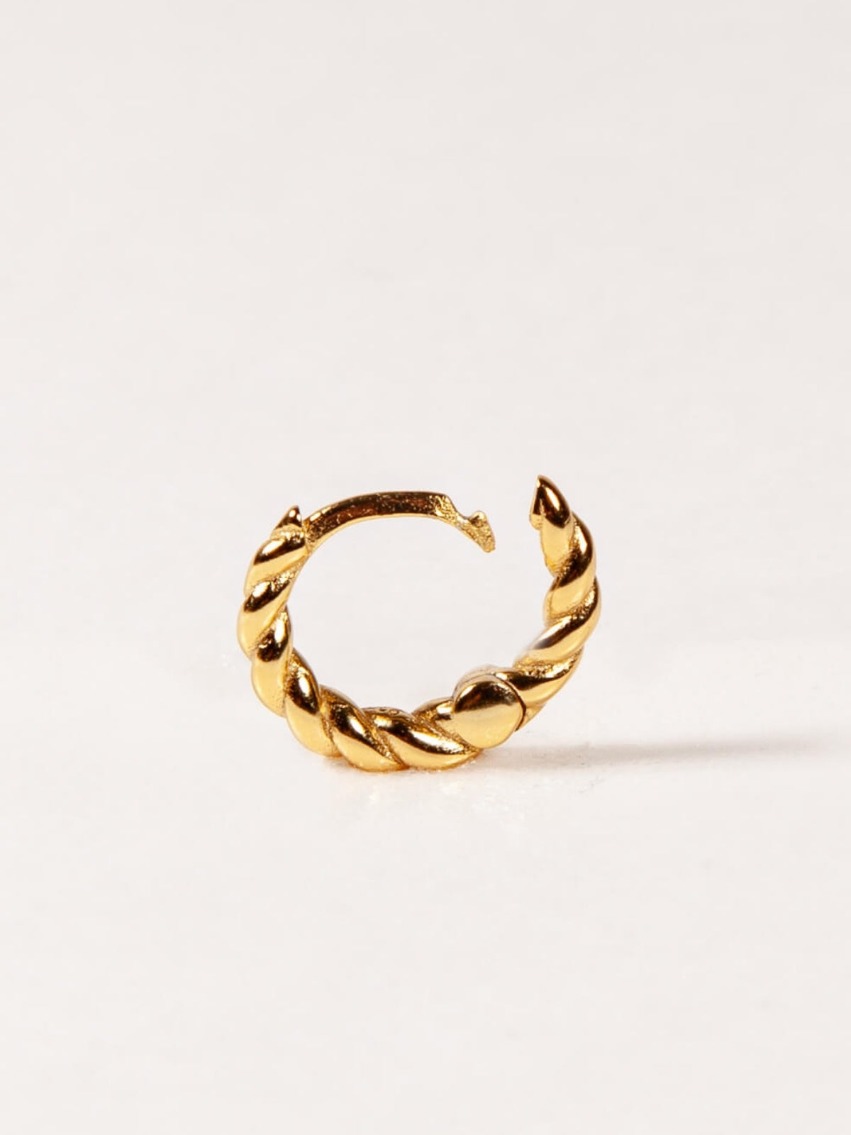 Gold twisted hoop earring on a white background