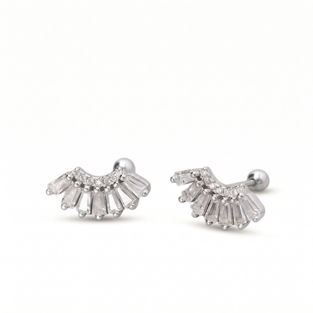A pair of silver crescent-shaped stud earrings with baguette-cut clear stones, shown on a clean white background.