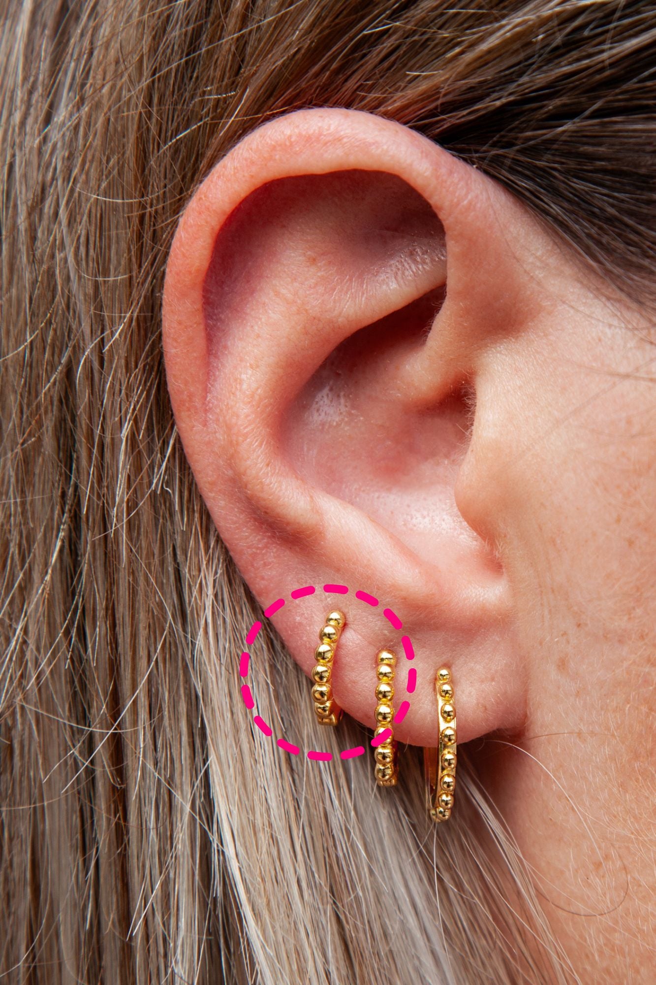 a woman's ear with hoops earrings with bead details 