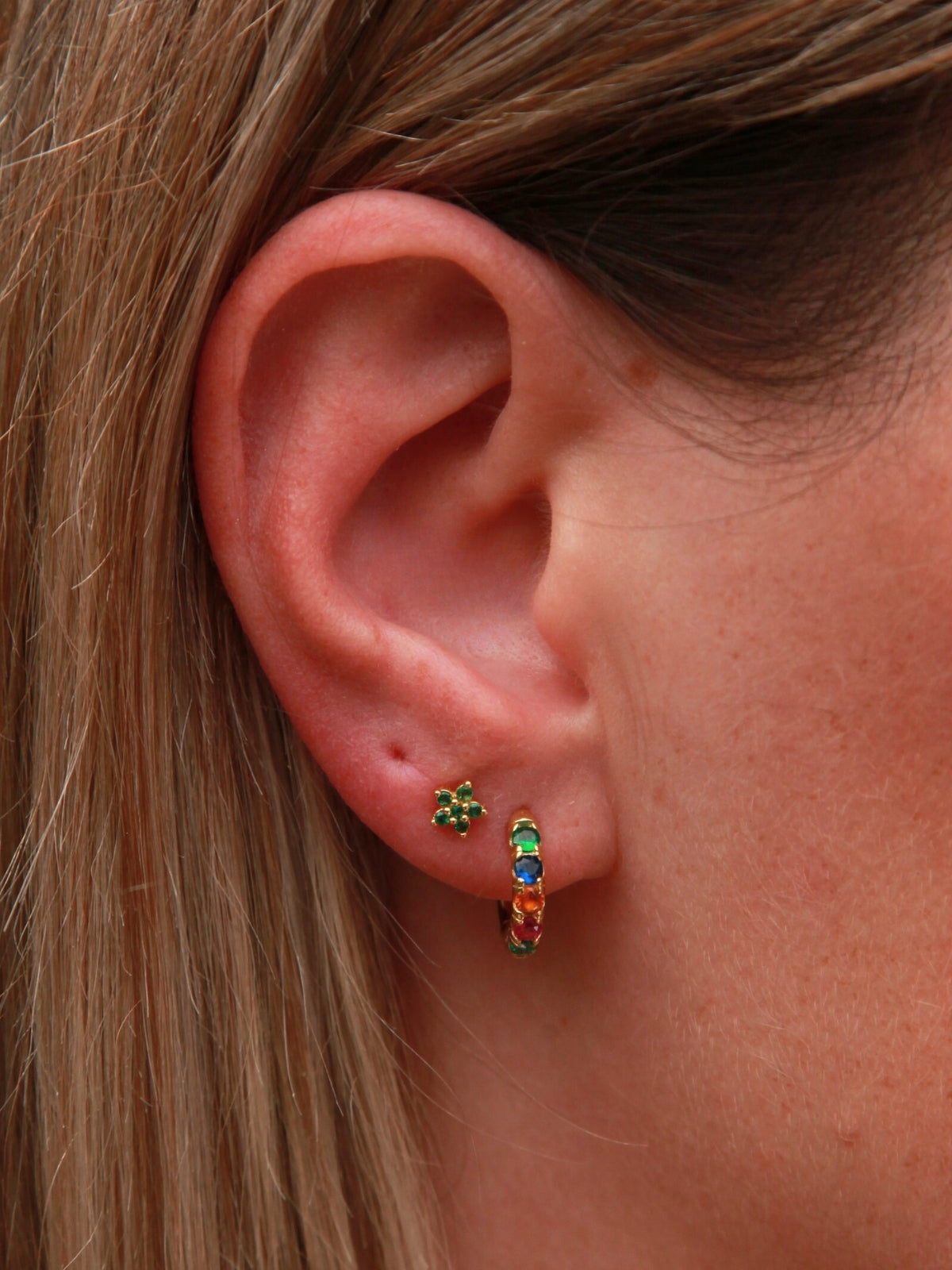 Close-up of an ear wearing colorful hoop earrings with a blurred background